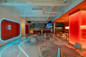 a room with tables and chairs and a tv on the wall at SilMiCore Hostel in Shanghai