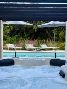 a pool with two umbrellas and two chairs and a swimming pool at CARPE DIEM Résidence Hôtelière in Lorgues