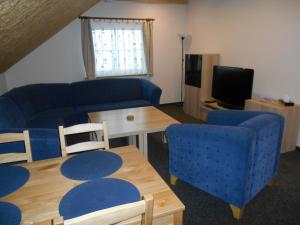 a living room with a blue couch and a table at Penzion Gerhard Klíny in Klíny