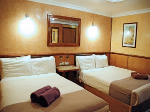 una camera d'albergo con due letti e uno specchio di Cricklewood Lodge Hotel a Londra