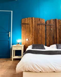 a bedroom with a large bed with a blue wall at L'ALCOVE HOTEL RESTAURANT in Villematier