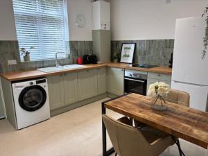 a kitchen with a washing machine and a table with chairs at Stylish Didsbury House in Manchester