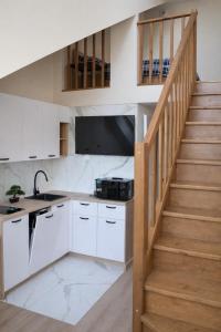 a kitchen with white cabinets and a stair case at Apartments Rajska 77 in Wrocław