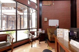 a room with a desk and a couch and windows at RedDoorz @ Cilandak Timur in Jakarta +32 photos