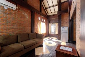 a living room with a couch and a brick wall at RedDoorz @ Cilandak Timur in Jakarta