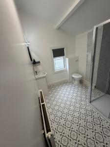 a white bathroom with a toilet and a sink at The Victoria Bar & Hotel in Wakefield