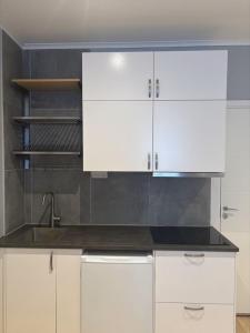 a kitchen with white cabinets and a sink at Villa Bäckagård Bed and Breakfast in Åstorp