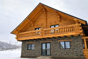 a log cabin with a deck on top of it at Pensiunea Sub Ursoi in Ieud