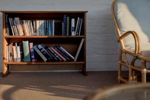 a book shelf filled with books next to a chair at Phillipskop Eco-Chalets in Stanford +42 photos