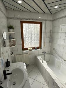 a white bathroom with a tub and a sink at Ferienwohnung Pellenz in Bremm +8 photos