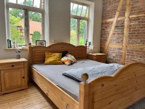 a bedroom with a wooden bed and a brick wall at Wendlandhof Lüggau in Dannenberg