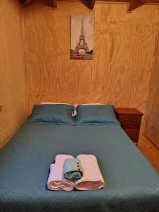 a bed with two towels on it with the eiffel tower at Cabañas Entrelagos - Naturaleza , parrilla y tranquilidad cerca de Huilo -Huilo in Choshuenco