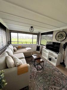 a living room with a couch and a television at De Polderhoeve in Heerhugowaard