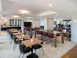a restaurant with tables and chairs and a bar at Mercure Sydney Blacktown in Blacktown