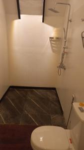a bathroom with a white toilet and a light at Misty Knuckles Cabana in Rangala