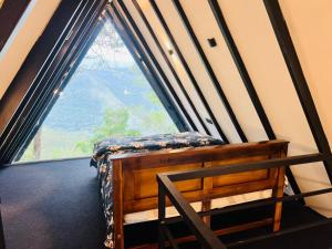 a room with a window with a bed in front of it at Misty Knuckles Cabana in Rangala