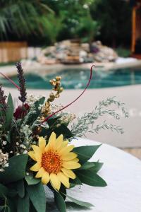 a vase of flowers on a table next to a pool at L'ALCOVE HOTEL RESTAURANT in Villematier