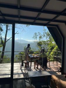 a man and a woman sitting at a table on a deck at Misty Knuckles Cabana in Rangala