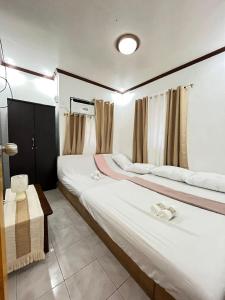 two twin beds in a room with curtains at Triple K Transient House in Butuan