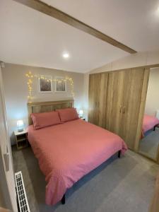 a bedroom with a large bed with pink sheets at 230 Unity Holiday Resort 6 Birth cosy and secure property next to all shops and entertainment passes optional in Brean