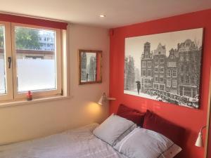 Dormitorio rojo con cama y ventana en Houseboat Westerdok en Ámsterdam