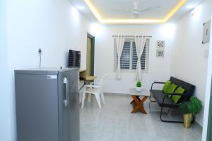 a kitchen and living room with a refrigerator and chairs at Hotel Aeroview Near Chennai Airport in Chennai