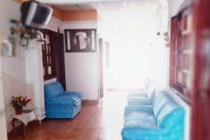 a living room with blue couches and a tv at Hotel Pisci Stars Sra in Saravena