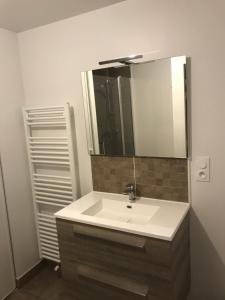 a bathroom with a white sink and a mirror at Appartement récent et à la déco moderne in Damgan
