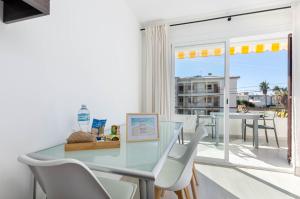 a dining room with a glass table and white chairs at YourHouse Llimonera in Port de Pollensa