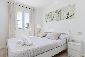 a white bedroom with a white bed and a window at YourHouse Llimonera in Port de Pollensa