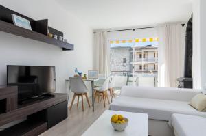 a living room with a white couch and a tv at YourHouse Llimonera in Port de Pollensa