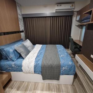 a bedroom with a bed with a blue and white comforter at Plus Sriracha Condo NEW Building in Si Racha +100 photos