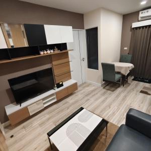 a living room with a large television and a table at Plus Sriracha Condo NEW Building in Si Racha