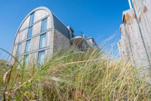 a building on the beach with tall grass at Residence Westduin in Sint Maartensvlotbrug