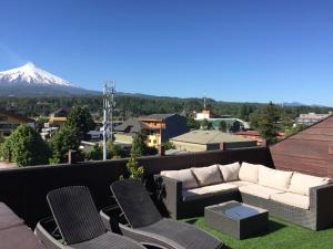 a couch and chairs on a balcony with a snow covered mountain at Rangi Pucon in Pucón