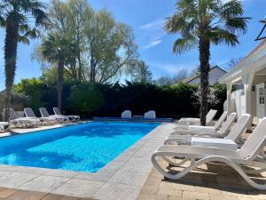 a pool with chaise lounge chairs and palm trees at De Heerlijkheid van Noordwelle Adults Only in Renesse