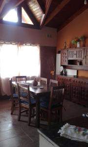 cocina con mesa, sillas y nevera en La Casita de Sil en Mina Clavero