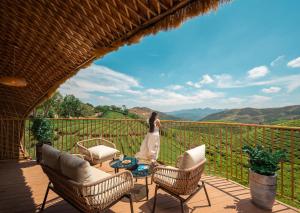 a woman standing on a patio with chairs and a table at Monticle Glamps in Vagamon