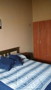 1 dormitorio con 1 cama con sábanas azules y armario de madera en La Casita de Sil en Mina Clavero