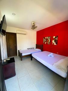 a room with two beds and a red wall at La Masia Hostal in Taganga