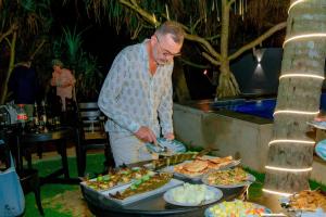 a man preparing a buffet of food on a table at Norea Sands in Bentota