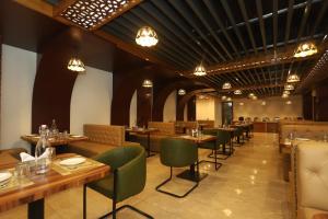 a restaurant with wooden tables and green chairs at The Udit By West Western - Central Heated and Air Cooled - River View & Roof Top cafe & Bar in Kasol