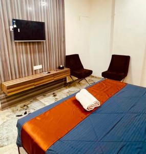 a room with a bed with two chairs and a television at Hotel Yash Residency in Ulhāsnagar
