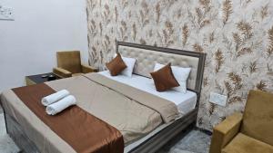 a bedroom with a bed with pillows and a chair at Hotel Yash Residency in Ulhāsnagar