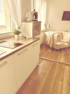 a kitchen with white cabinets and a living room at Trio Apartments in Ostrava