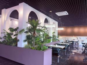 a restaurant with tables and chairs and plants at Hotel Eden24 Novembre in Kinshasa