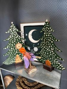a shelf with two christmas trees and a picture at Maison d'hôtes des Mondfänger in Meisenthal +41 photos