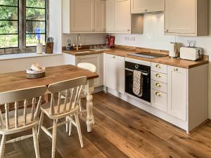 a kitchen with white cabinets and a wooden table at The Old School in Kettlewell