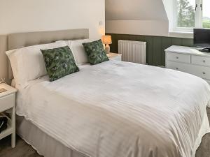 a bedroom with a white bed with two green pillows at The Old School in Kettlewell