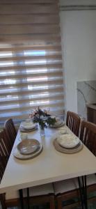 a white table with plates and flowers on it at Apartman DMD in Bijelo Polje